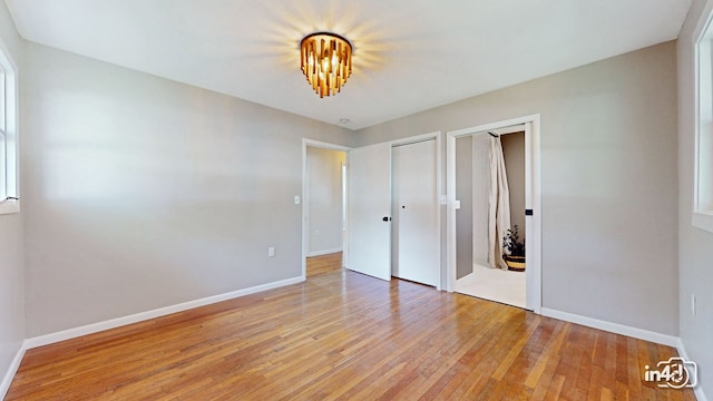 unfurnished bedroom featuring light wood-style floors, baseboards, and two closets