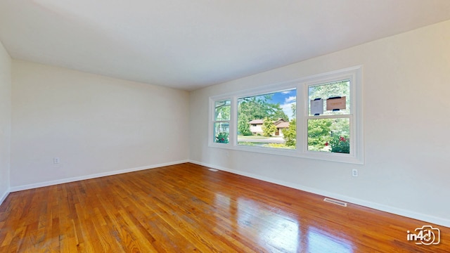 unfurnished room featuring visible vents, baseboards, and hardwood / wood-style flooring