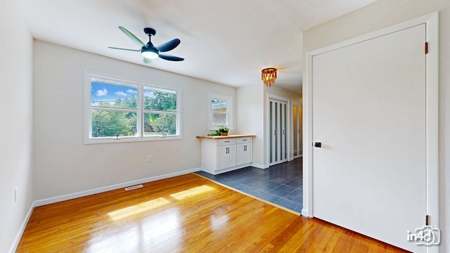 unfurnished room with visible vents, wood finished floors, baseboards, and ceiling fan