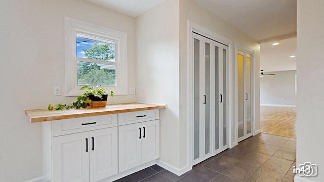 corridor with recessed lighting, baseboards, and dark tile patterned flooring