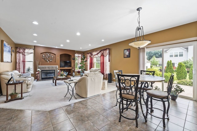 dining space featuring a wealth of natural light, a glass covered fireplace, recessed lighting, and tile patterned floors