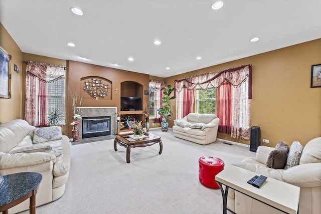 living area with a tiled fireplace, recessed lighting, and carpet