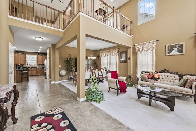 living area featuring a chandelier, light tile patterned floors, light colored carpet, and baseboards