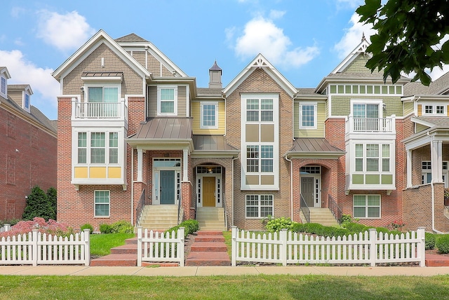 view of front of house with brick siding, a fenced front yard, metal roof, and a standing seam roof