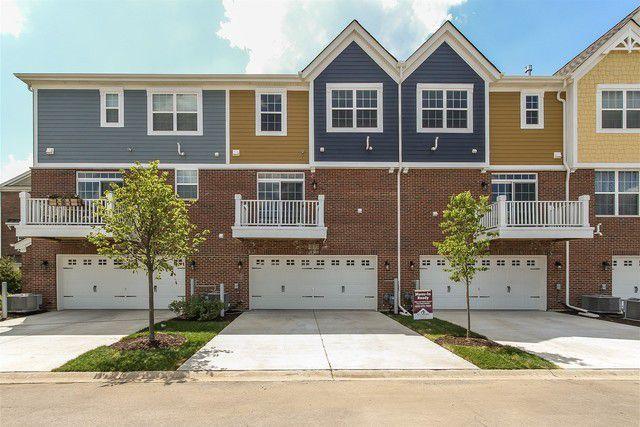 multi unit property featuring brick siding, cooling unit, concrete driveway, and an attached garage