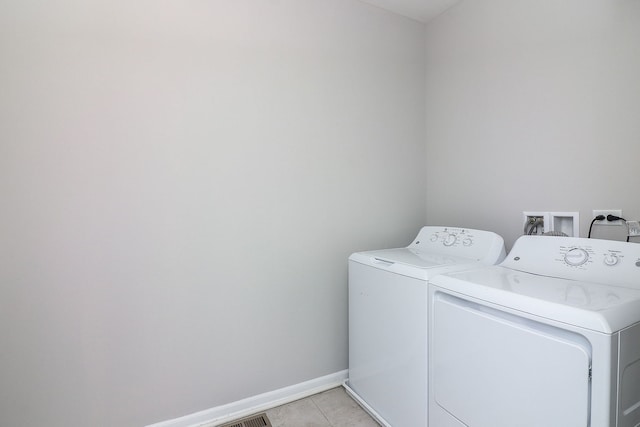 laundry area featuring laundry area, light tile patterned floors, baseboards, and washer and clothes dryer