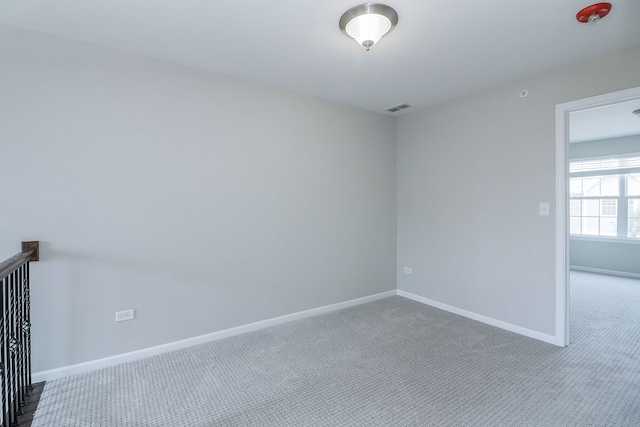 carpeted empty room featuring baseboards and visible vents