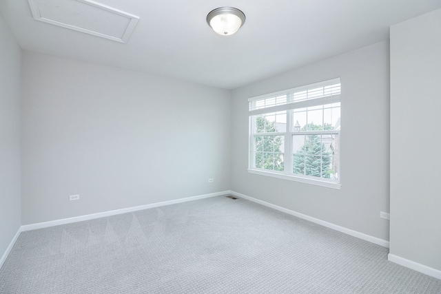 carpeted empty room with baseboards and attic access