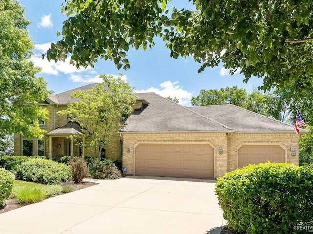 view of front of property with brick siding, concrete driveway, an attached garage, and a shingled roof