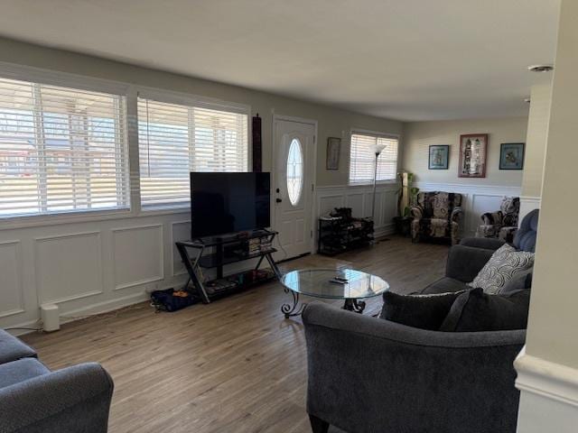 living area featuring a decorative wall, wood finished floors, and a wainscoted wall