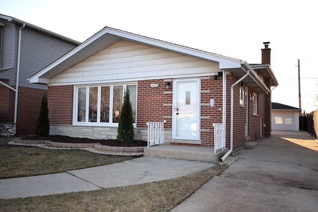 view of front of home featuring brick siding, a garage, a chimney, and an outdoor structure