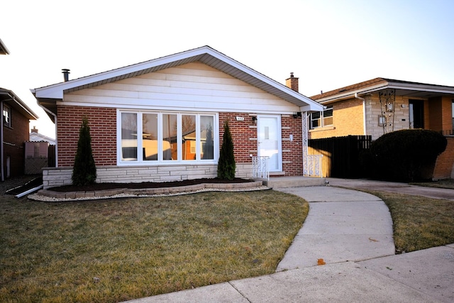 bungalow-style house featuring brick siding, a chimney, a front lawn, and fence