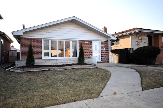 bungalow-style home featuring a front yard, fence, brick siding, and a chimney