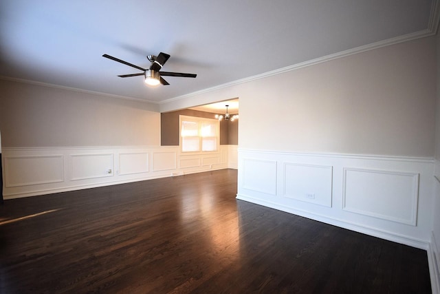 spare room featuring crown molding, dark wood-style floors, ceiling fan with notable chandelier, and wainscoting