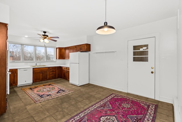 kitchen featuring a ceiling fan, a sink, white appliances, light countertops, and hanging light fixtures