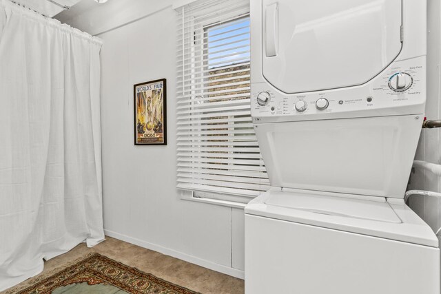 clothes washing area featuring laundry area, baseboards, and stacked washer and clothes dryer