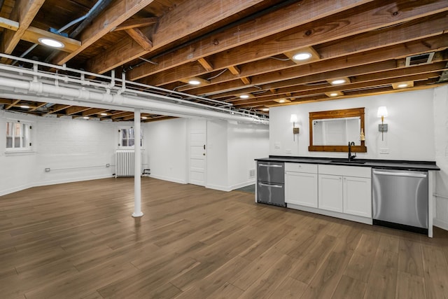 basement with dark wood-type flooring, a sink, radiator, baseboards, and indoor bar