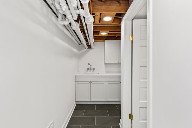 interior space with light countertops, dark tile patterned floors, baseboards, and a sink