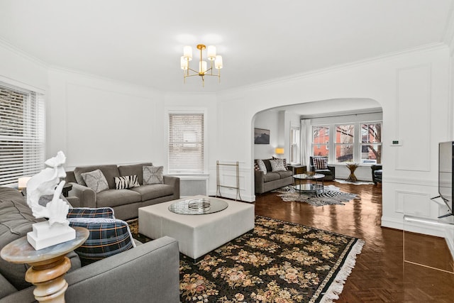 living area with crown molding, arched walkways, and a chandelier