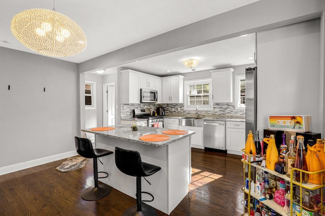 11551 S Justine St, Chicago, IL 60643 - kitchen featuring appliances with stainless steel finishes, tasteful backsplash, dark wood-type flooring, white cabinets, and a chandelier