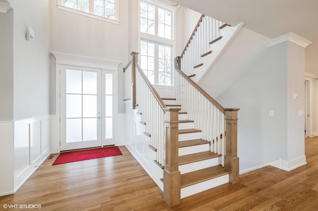 foyer featuring stairway, wainscoting, a towering ceiling, and wood finished floors