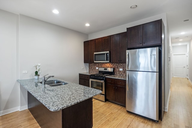 kitchen with light wood-type flooring, a sink, tasteful backsplash, stainless steel appliances, and dark brown cabinets