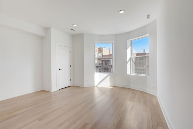 empty room with light wood-style flooring, recessed lighting, visible vents, and baseboards