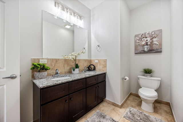 bathroom featuring toilet, decorative backsplash, double vanity, and a sink