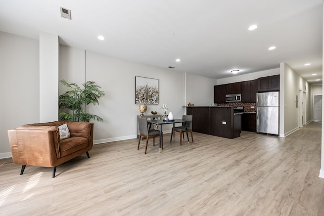 kitchen with appliances with stainless steel finishes, light wood-style floors, dark brown cabinets, baseboards, and open floor plan
