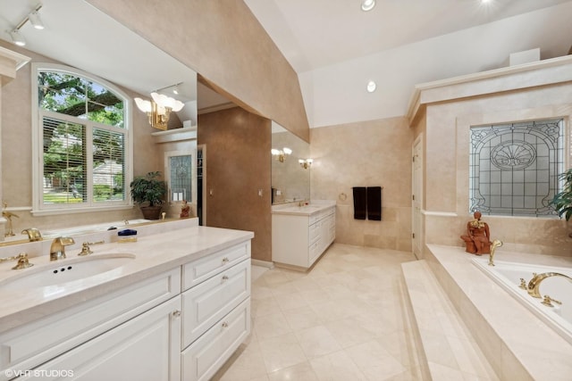 bathroom featuring a sink, a garden tub, two vanities, and a chandelier