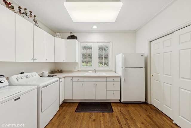 laundry room featuring wood finished floors, cabinet space, a sink, crown molding, and independent washer and dryer