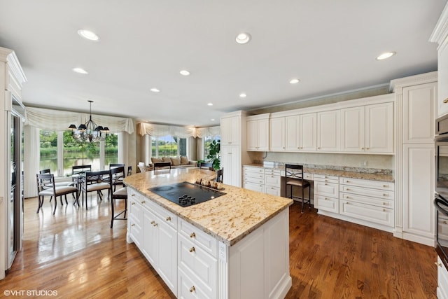 kitchen with an inviting chandelier, black electric stovetop, wood finished floors, and a kitchen island