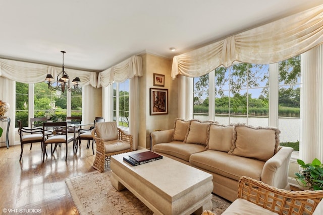 living area with an inviting chandelier, wood finished floors, and a water view