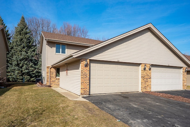 view of property exterior with aphalt driveway, a garage, a lawn, and brick siding