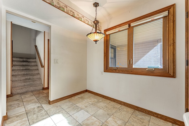 empty room featuring stairway and baseboards