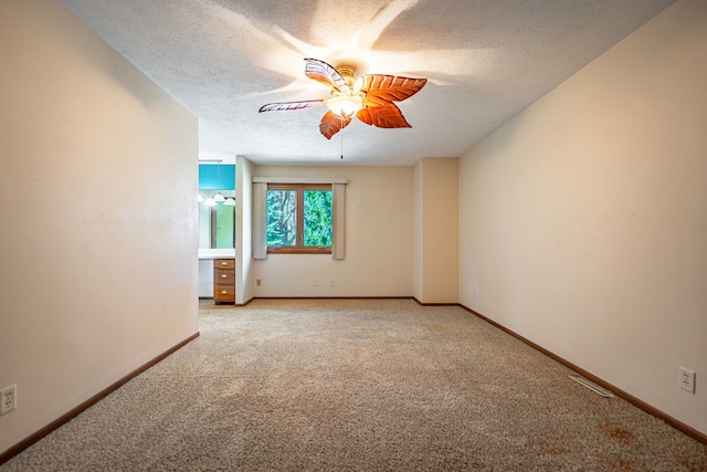 spare room featuring light colored carpet, a ceiling fan, baseboards, and a textured ceiling