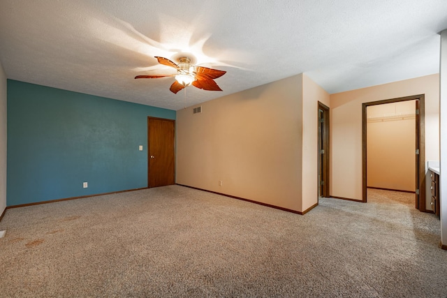 unfurnished room featuring visible vents, baseboards, light colored carpet, a textured ceiling, and a ceiling fan