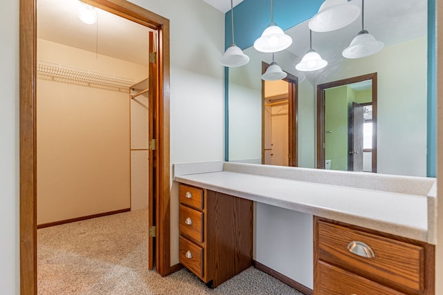 bathroom featuring vanity, a walk in closet, and baseboards