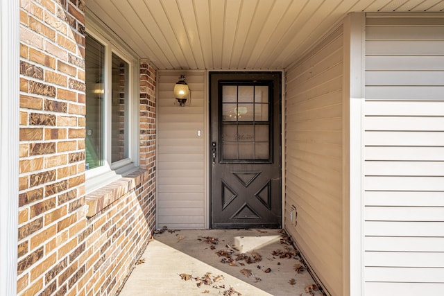 property entrance with brick siding and a porch