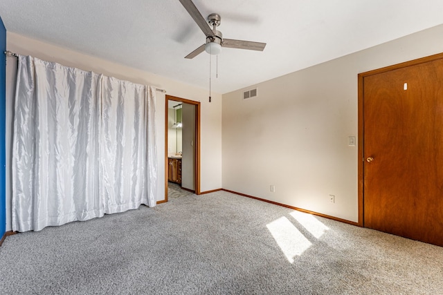 carpeted spare room with visible vents, baseboards, and a ceiling fan