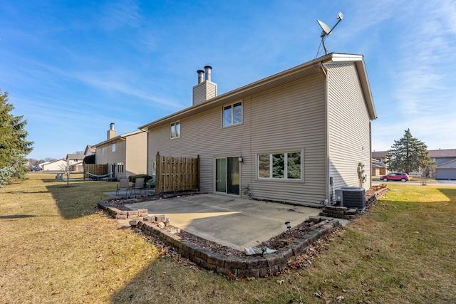 back of house featuring cooling unit, a patio, a lawn, and a chimney