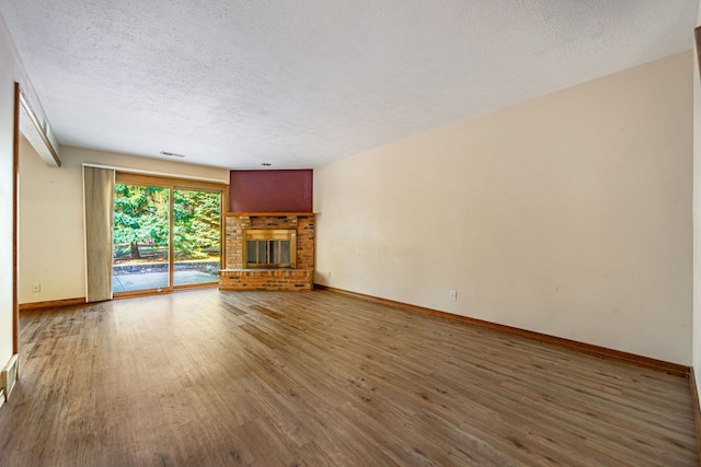 unfurnished living room with visible vents, a fireplace, a textured ceiling, and wood finished floors