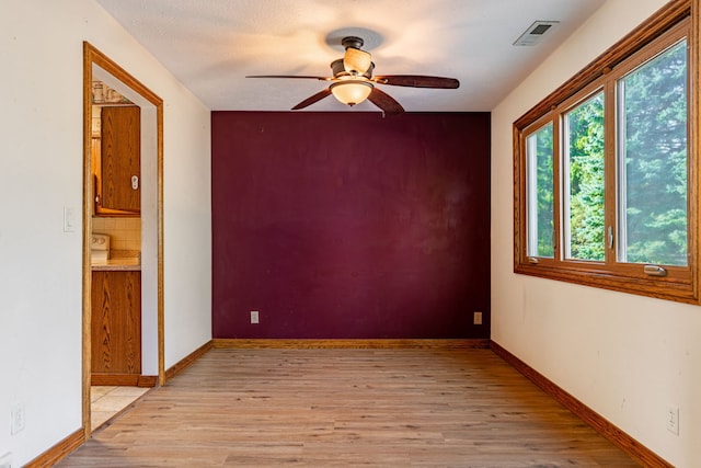 spare room featuring visible vents, light wood-style flooring, baseboards, and ceiling fan