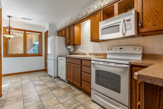 kitchen with tasteful backsplash, visible vents, brown cabinetry, white appliances, and a sink