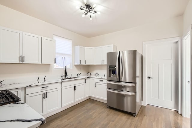 kitchen featuring a sink, stainless steel fridge, light wood-style floors, and light countertops