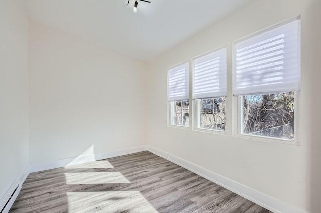 empty room with a baseboard radiator, baseboards, and a healthy amount of sunlight