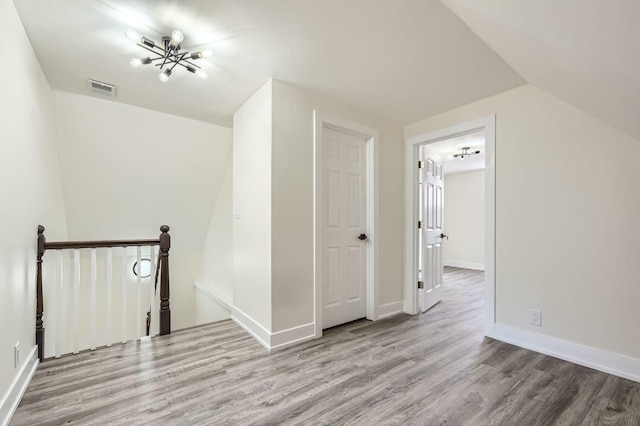 additional living space with wood finished floors, visible vents, and baseboards