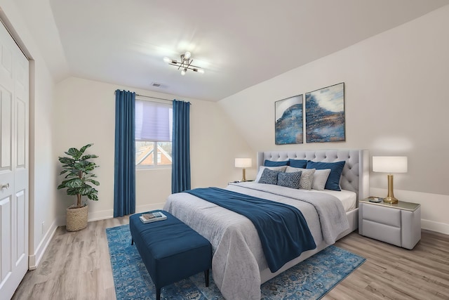 bedroom featuring lofted ceiling, light wood-style floors, visible vents, and baseboards