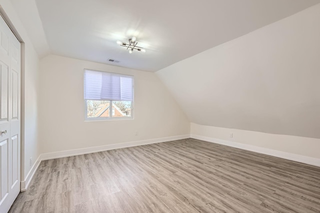 bonus room with lofted ceiling, baseboards, visible vents, and light wood finished floors