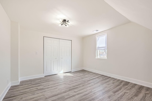 unfurnished bedroom with a closet, baseboards, and light wood-style floors